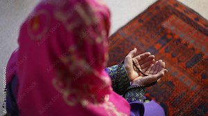 Closeup of a muslim woman hands while praying with prayer beads on prayer rug.