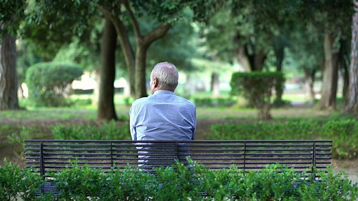 Man sitting on his own on a park bench in a park - Free Stock Video