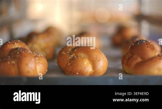 Lens shifting focus and exposure, bringing front braided roll sharp on tray, showing seeded crust. Bakery, bread, artisanal, golden, sesame, poppy, warm Stock Video Footage - Alamy
