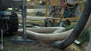 Drilling mud and rock debris flowing in plastic pipe from rotary drill pit