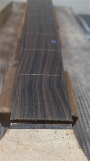 Here's a little time lapse of my fingerboard leveling and finishing process. I get the board flat with 220 grit then alternate between a wood stabilizer and sandpaper up to 1500 grit. It creates a beautifully finished board that shows off the grain of the ebony beautifully and is dead level. This board also features crushed opal face dots. #grogguitars #luthier #satisfying #woodworking #customguitar