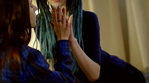 Two beautiful women are sitting on the bed together and holding hands.