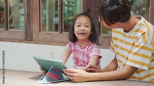 The mother is teaching her child, creating environment for learning. They're connected to the internet wirelessly and modern technology for home schooling and enjoying the knowledge and entertainment.