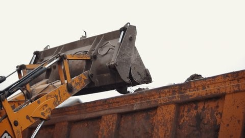 clip-3962359315-tractor-front-bucket-unloading-soil-into-truck