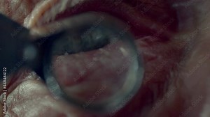 A goldsmith in jewelry checks the quality of luxury brilliant diamonds. Old man with a vintage magnifying glass looks at a diamond to determine its purity . Closeup of goldsmith's eye in workshop .