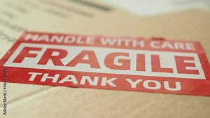 A cardboard box marked with a caution label for fragile goods handling during shipping