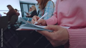 The girl makes notes in a notebook, write in a notebook at a conference, the girl writes with a pen in a notebook