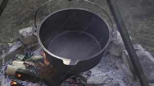 Cast iron pot heating on an open fire at outdoor campsite
