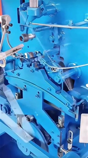 Operating an automated blue industrial machine to manufacture metal clips for office or paper use