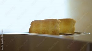 Sliced Roasted White Bread Popping From Electric Toaster. Toaster in Kitchen Slow Motion Making Toasts Bread at Breakfast Closeup. Roasted Toast Bread Popping up From Toaster Machine Close Up.