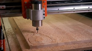 An automated cnc wood router cuts out a wooden cutting board. Shooting in motion along the route according to the program