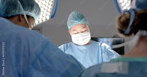 Diverse female surgeons operating on patient in operating theatre, slow motion