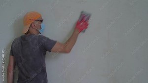 Man doing repair in new apartment and smoothing wall. Detail of a man cleaning a wall and applying putty for alignment during apartment repair