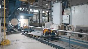 Automated factory machinery deals with the tube manufacturing process. Automated factory equipment with a rolling mechanism moving the steel tube. Automated tube production line at the factory.