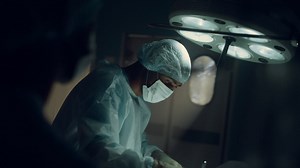 Focused surgeon performing operation in dark sterile hospital operating room. Free Stock Video Footage