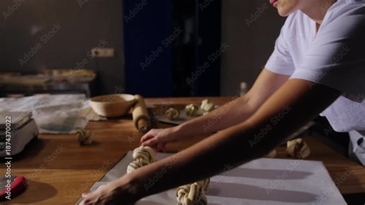 Baker places shaped cinnamon buns onto a baking tray, spacing each piece evenly before baking. Hands arrange fresh dough, showing the final preparation step in the Swedish cinnamon bun process.