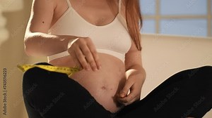 Pregnant woman measuring her belly. Unrecognizable pregnant woman measuring belly diameter with yellow measure band tape, monitoring body changes weight gain dimensions. Pregnancy maternity concept.