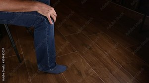 male white hand on knee while leg repeatedly uncontrollably shakes up and down due to restless leg syndrome. perhaps a sign of being deep in thought or tired of waiting for what he wants