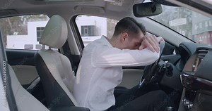 Sad male businessman crying while sitting in a car. Crisis and problems in business. Depressed man