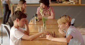 Two children playing chess in cafe. Chess is a strategic game that stimulates critical thinking, problem-solving, and cognitive skills. Kids mentally stimulating indoor activity. People lifestyle.