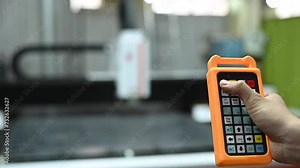 A man operates a CNC machine using a remote control. Laser cutting of metal. Sparks.