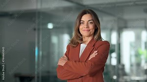 Happy confident professional middle aged business woman in office, portrait. Smiling older mature Latin corporate leader, female executive manager wearing suit standing arms crossed looking at camera.