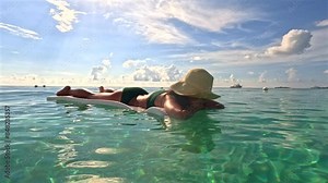 Beautiful woman sunbathing on Caribbean sea with clear sky and stunning clouds background in Jamaica on the 7 Mile Beach. Tropical summer vacation and nature environment concept