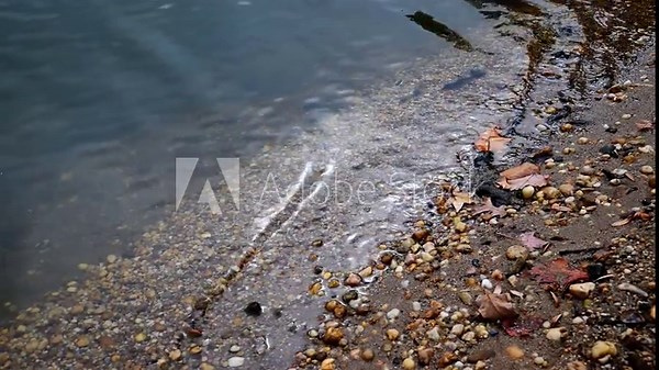 Sandy shore with rounded colorful pebbles in the Raritan River, New Jersey, USA.