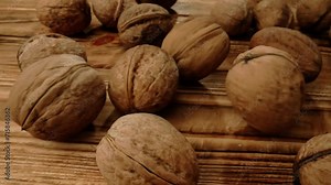 Close up shot of food ingredients on the wooden surface in studio. Top view freshly roasted unpeeled walnuts in shells scattered falling on the table.