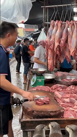 Asian Traditional Market: Man Selling Fresh Beef Amid Crowded Muddy Market Scene.