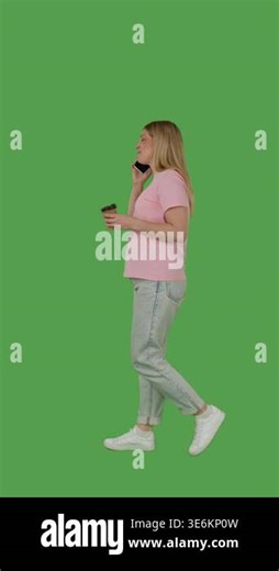A person is walking and using a smartphone in one hand with a cup in the other on green screen, chroma key. Side view, vertical video Stock Video Footage - Alamy