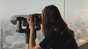 Person looking in binoculars telescope on observation deck for tourist. Tower sky viewpoint top floor. City skyline panorama at day time. Travel, tourism, outdoor lifestyle holiday vacation. Back view