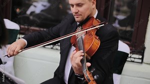 Handsome guy playing violin outdoors. Violint play music for the wedding. Violin under the open sky. Love of music concept.