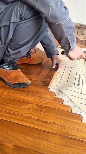 Carpenter installing wooden floor panels in herringbone pattern