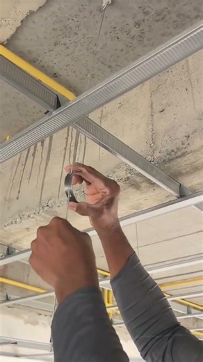 Inserting a long metal bar into support sleeve to hold steel sections during roof frame installation