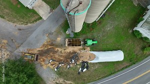 Aerial top down of silage process on farmstead with silo. Tractor with Excavator transporting corn and grain.