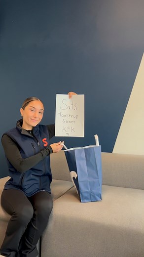 🩷Der har været en hemmelighed i luften… 🩷 Posen går fra hånd til hånd – og nu kan vi endelig afsløre det! 🎉 Vi åbner SATS KFK Taastrup – kun for kvinder – den 17. november 2025! 💪💖 Glæd dig til et helt nyt træningsunivers, hvor fællesskab, styrke og energi er i fokus! | SATS Taastrup