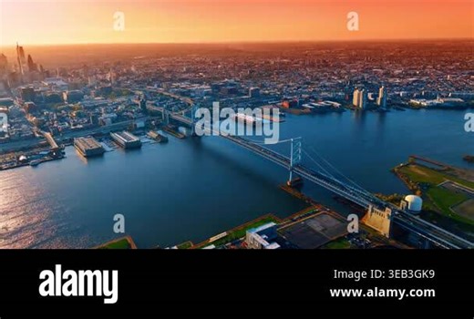 Flying closer to the Benjamin Franklin Bridge across the Delaware River. Panorama of Philadelphia, Pennsylvania, USA at sunset time.