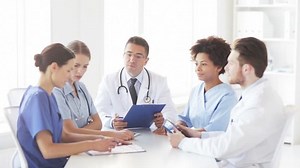 hospital, profession, people and medicine concept - group of doctors with clipboard meeting and discussing something at medical office