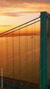 Blue massive supports of Whitestone bridge in the orange light. Beautiful picture of sunset over East River. Vertical video