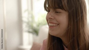 A teenage girl hanging out in a living room and talking to her friends.