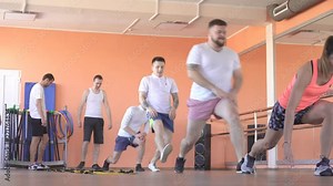 Beautiful caucasian girl trainer shows men exercises for weight loss and health in a modern fitness center, group classes in the gym