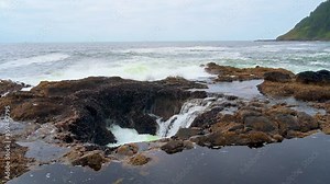 Water rushes into Thor's Well on the Oregon coast, a natural saltwater fountain in rocky terrain. 4K UHD video.