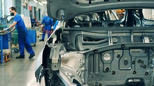 Car manufacturing worker assembling a car body on an assembling line
