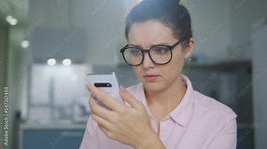 Angry irritated woman with hair bun having problems with smartphone, bad internet connection, poor connection for calls, cons of distant learning or working