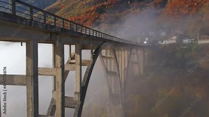 Aerial video of the magnificent Djurdjevica Bridge over the Tara river canyon in the northern part of Montenegro. Beautiful morning fog moves through the arches of the bridge. Shot in the fall season