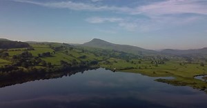 Aerial 4K Drone footage of Lake Bala, North Wales. Footage pulls back and shows a peak hill top on L