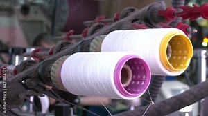 Rolls of industrial cotton fabric for textile production of clothing on a machine. Spinning production line. Spinning machinery with spindles and wool yarns.