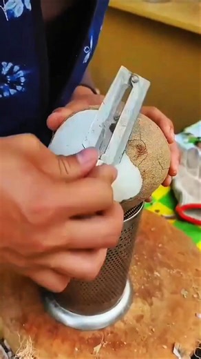 Worker scrapes coconut carefully showing precise preparation method
