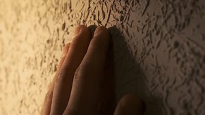Male hand touching a convex wall with a decorative convex surface, close-up